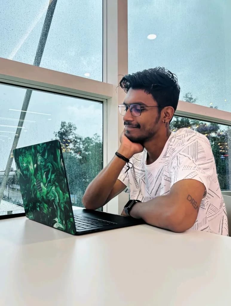 Ansu working on laptop by rain window